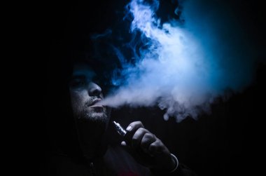 Bir mod tutarak Vaping adam. Buhar bulutu. Siyah arka plan. Vaping çok duman ile elektronik sigara