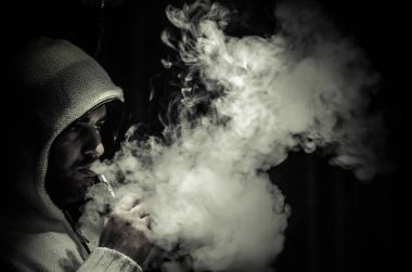 Bir mod tutarak Vaping adam. Buhar bulutu. Siyah arka plan. Vaping çok duman ile elektronik sigara