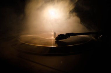 Pikap vinil plak çalar. Retro ses ekipmanları için disk jokey. Dj mix ve müzik çalmak için ses teknolojisi. Yangın arka plan duman ile yanan karşı oynanan vinil kaydı. Vintage