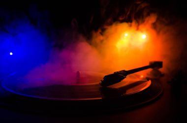 Pikap vinil plak çalar. Retro ses ekipmanları için disk jokey. Dj mix ve müzik çalmak için ses teknolojisi. Yangın arka plan duman ile yanan karşı oynanan vinil kaydı. Vintage