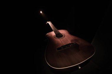 Müzik konsepti. Akustik gitar ile kopya alanı dumanla ışık demeti altında karanlık bir arka plan üzerinde izole. Gitar telleri, yakın çekim. Seçici odak. Yangın etkileri