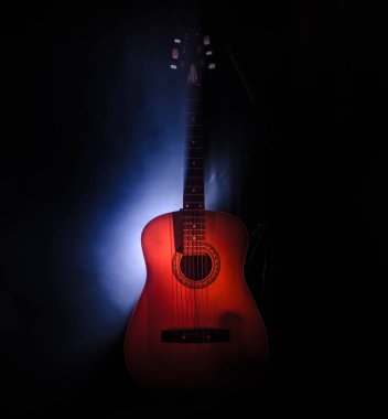 Müzik konsepti. Akustik gitar ile kopya alanı dumanla ışık demeti altında karanlık bir arka plan üzerinde izole. Gitar telleri, yakın çekim. Seçici odak. Yangın etkileri