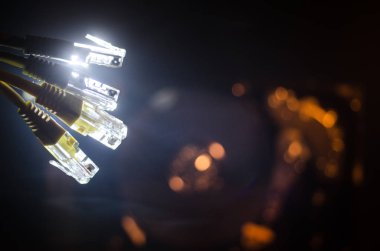 Ağ anahtarı ve ethernet kabloları, global iletişim sembolüdür. Işıklar ve duman ile koyu arka plan üzerinde renkli ağ kabloları. Seçici odak