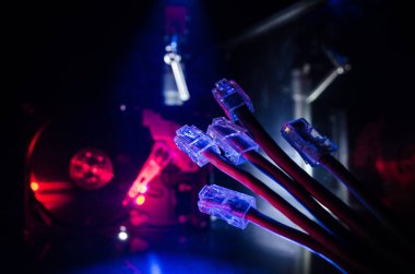 Ağ anahtarı ve ethernet kabloları, global iletişim sembolüdür. Işıklar ve duman ile koyu arka plan üzerinde renkli ağ kabloları. Seçici odak