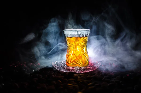 Türkischer Azerbaijan-Tee in traditionellem Glas und Kanne auf schwarzem Hintergrund mit Licht und Rauch. Armudu-Pokal — Stockfoto