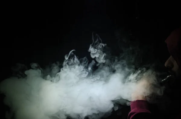 Вейп-людина тримає мод. Хмара пара. Чорний фон. Ставка на електронну сигарету з великою кількістю диму — стокове фото