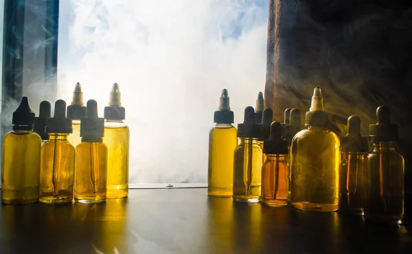 Vape concept. Smoke clouds and vape liquid bottles on window with sunlight on background. Light effects. Useful as background or vape advertisement or vape background. Close up — Stock Photo, Image