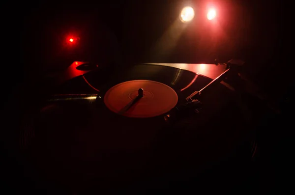 Turntable vinyl record player. Retro audio equipment for disc jockey. Sound technology for DJ to mix & play music. Vinyl record being played against burning fire background with smoke. Vintage — Stock Photo, Image