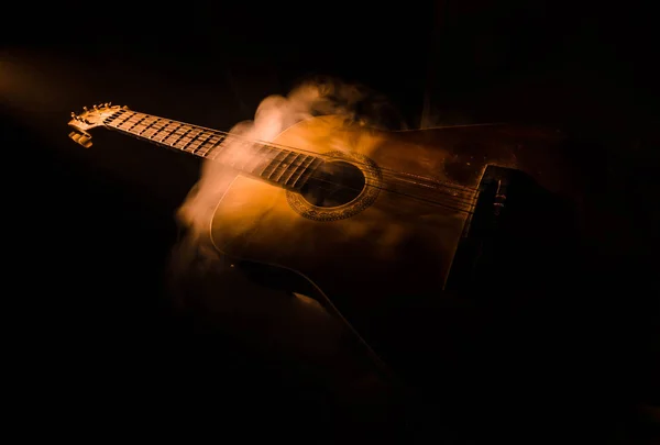 Conceito musical. Guitarra acústica isolada em fundo escuro sob feixe de luz com fumaça com espaço de cópia. Cordas de guitarra, de perto. Foco seletivo. Efeitos de fogo — Fotografia de Stock