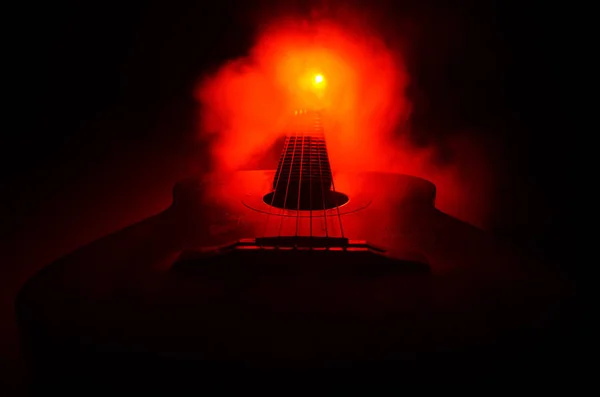 Musikkonzept. Akustikgitarre isoliert auf dunklem Hintergrund unter Lichtkegel mit Rauch und Kopierraum. Gitarrensaiten, hautnah. Selektiver Fokus. Feuereffekte — Stockfoto