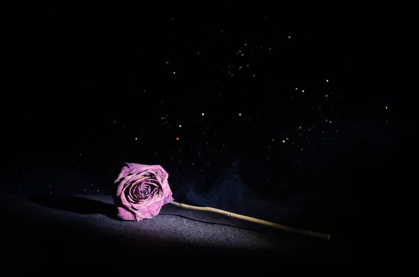 A wilting rose signifies lost love, divorce, or a bad relationship, dead rose on dark background