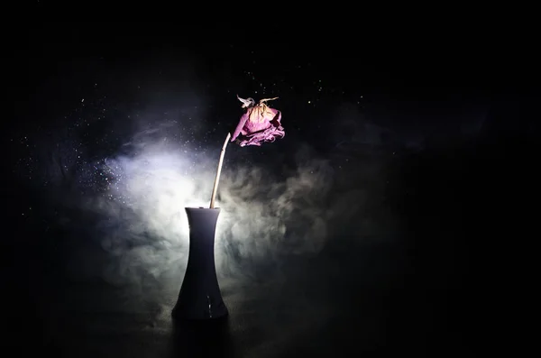 A wilting rose signifies lost love, divorce, or a bad relationship, dead rose on dark background