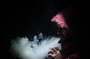 Bir mod tutarak Vaping adam. Buhar bulutu. Siyah arka plan. Vaping çok duman ile elektronik sigara