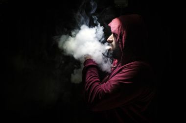 Bir mod tutarak Vaping adam. Buhar bulutu. Siyah arka plan. Vaping çok duman ile elektronik sigara