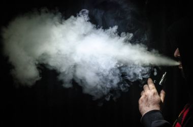 Bir mod tutarak Vaping adam. Buhar bulutu. Siyah arka plan. Vaping çok duman ile elektronik sigara