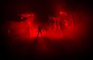 Zaman kavramı. Duman ile hourglasses ve karanlık bir arka plan ışıkları arasında duran bir adam silüeti.