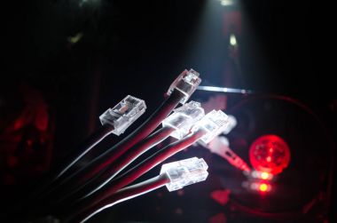 Ağ anahtarı ve ethernet kabloları, global iletişim sembolüdür. Işıklar ve duman ile koyu arka plan üzerinde renkli ağ kabloları. Seçici odak