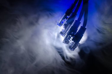Ağ anahtarı ve ethernet kabloları, global iletişim sembolüdür. Işıklar ve duman ile koyu arka plan üzerinde renkli ağ kabloları. Seçici odak