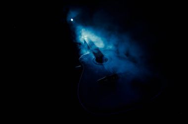 Müzik konsepti. Akustik gitar ile kopya alanı dumanla ışık demeti altında karanlık bir arka plan üzerinde izole. Gitar telleri, yakın çekim. Seçici odak. Yangın etkileri