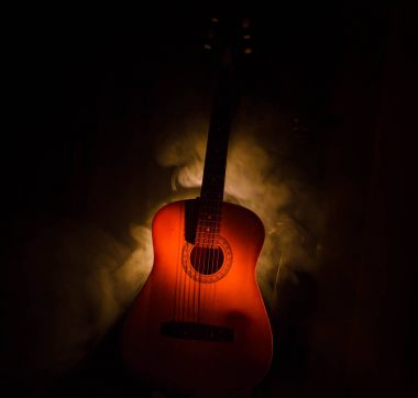 Müzik konsepti. Akustik gitar ile kopya alanı dumanla ışık demeti altında karanlık bir arka plan üzerinde izole. Gitar telleri, yakın çekim. Seçici odak. Yangın etkileri
