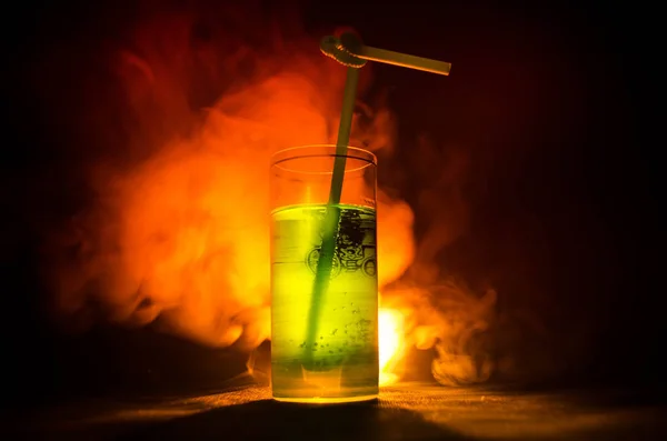 Glas grüner Cocktail mit Stroh auf dunklem Hintergrund mit Rauch und Hintergrundbeleuchtung. — Stockfoto