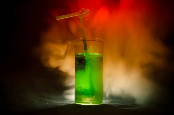 Vaso de cóctel verde con paja sobre fondo oscuro con humo y contraluz . — Foto de Stock