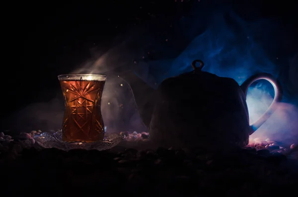 Teh Azerbaijan Turki dalam kaca tradisional dan pot dengan latar belakang hitam dengan lampu dan asap. Armudu cangkir tradisional — Stok Foto