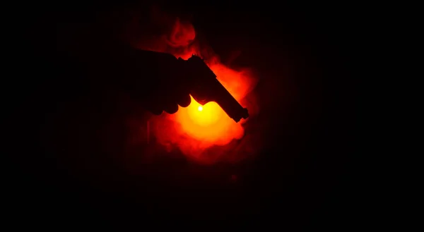 Pistolet à main mâle sur fond noir avec feux arrière de couleur fumée (jaune orange rouge blanc), concept tueur de la mafia — Photo