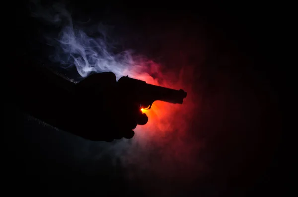 Pistolet à main mâle sur fond noir avec feux arrière de couleur fumée (jaune orange rouge blanc), concept tueur de la mafia — Photo