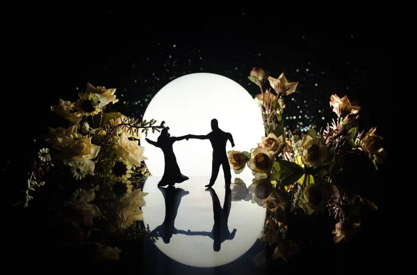 Siluetas de pareja de juguetes bailando bajo la Luna por la noche. Figuras de hombres y mujeres enamorados bailando a la luz de la luna — Foto de Stock