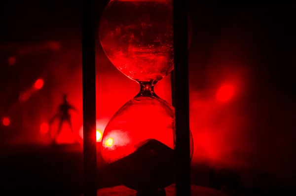 Concepto de tiempo. Silueta de un hombre parado entre clepsidras con humo y luces sobre un fondo oscuro . — Foto de Stock