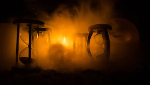 Concepto de tiempo. Silueta de un hombre parado entre clepsidras con humo y luces sobre un fondo oscuro . —  Fotos de Stock