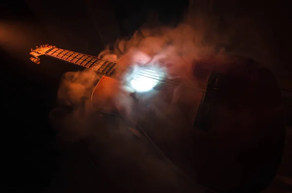 Conceito musical. Guitarra acústica isolada em fundo escuro sob feixe de luz com fumaça com espaço de cópia. Cordas de guitarra, de perto. Foco seletivo. Efeitos de fogo — Fotografia de Stock