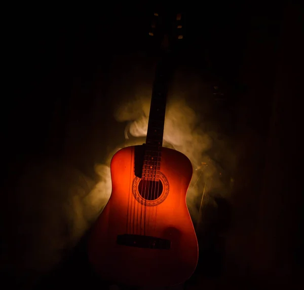 Conceito musical. Guitarra acústica isolada em fundo escuro sob feixe de luz com fumaça com espaço de cópia. Cordas de guitarra, de perto. Foco seletivo. Efeitos de fogo — Fotografia de Stock