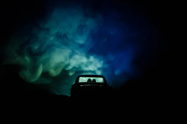 Silhueta de carro com casal dentro no fundo escuro com luzes e fumaça. Cena romântica. Conceito de amor — Fotografia de Stock