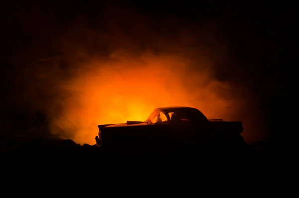 Un coche en llamas sobre un fondo oscuro. Incendio de coches, después de acto de vandalismo o indicativo de la carretera — Foto de Stock