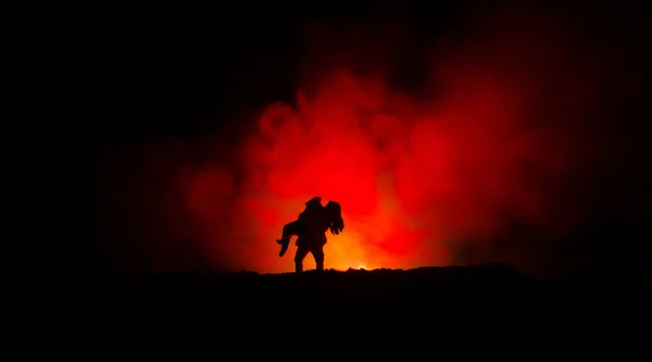 Sylwetka człowieka, trzymając się kobieta. Ratunkowej koncepcji Zbawiciela. Uciec od ognia lub niebezpieczeństwo. Klepsydra, ogień — Zdjęcie stockowe