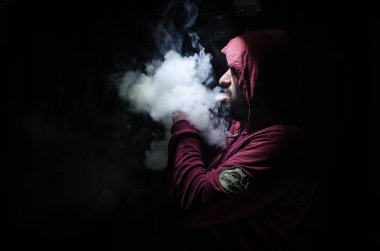Bir mod tutarak Vaping adam. Buhar bulutu. Siyah arka plan. Vaping çok duman ile elektronik sigara