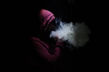 Bir mod tutarak Vaping adam. Buhar bulutu. Siyah arka plan. Vaping çok duman ile elektronik sigara