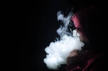 Bir mod tutarak Vaping adam. Buhar bulutu. Siyah arka plan. Vaping çok duman ile elektronik sigara