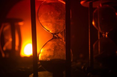 Zaman kavramı. Duman ile hourglasses ve karanlık bir arka plan ışıkları arasında duran bir adam silüeti.