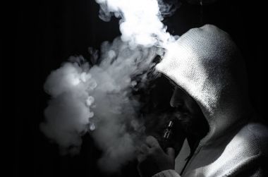 Bir mod tutarak Vaping adam. Buhar bulutu. Siyah arka plan. Vaping çok duman ile elektronik sigara