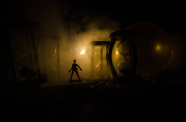 Zaman kavramı. Duman ile hourglasses ve karanlık bir arka plan ışıkları arasında duran bir adam silüeti.