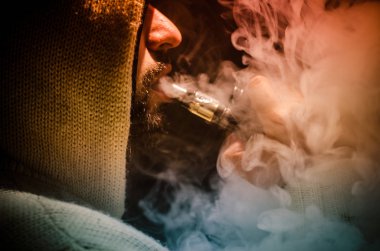 Bir mod tutarak Vaping adam. Buhar bulutu. Siyah arka plan. Vaping çok duman ile elektronik sigara