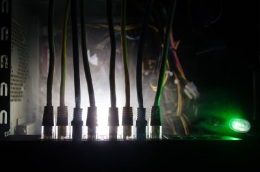 Ağ anahtarı ve ethernet kabloları, global iletişim sembolüdür. Işıklar ve duman ile koyu arka plan üzerinde renkli ağ kabloları. Seçici odak