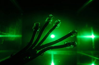 Ağ anahtarı ve ethernet kabloları, global iletişim sembolüdür. Işıklar ve duman ile koyu arka plan üzerinde renkli ağ kabloları. Seçici odak