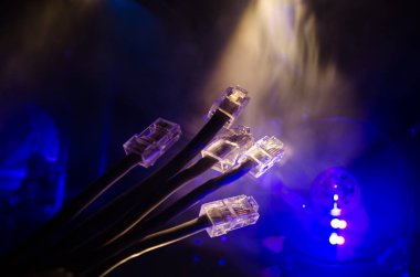 Ağ anahtarı ve ethernet kabloları, global iletişim sembolüdür. Işıklar ve duman ile koyu arka plan üzerinde renkli ağ kabloları. Seçici odak