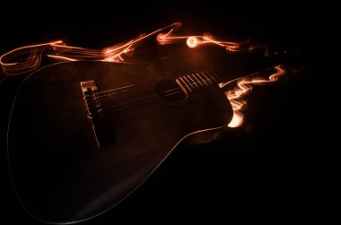 Müzik konsepti. Akustik gitar ile kopya alanı dumanla ışık demeti altında karanlık bir arka plan üzerinde izole. Gitar telleri, yakın çekim. Seçici odak. Yangın etkileri