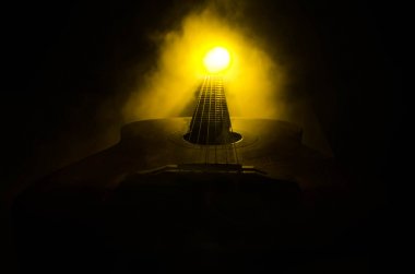 Müzik konsepti. Akustik gitar ile kopya alanı dumanla ışık demeti altında karanlık bir arka plan üzerinde izole. Gitar telleri, yakın çekim. Seçici odak. Yangın etkileri