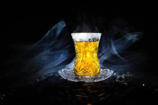 Turkish Azerbaijan tea in traditional glasse and pot on black background with lights and smoke. Armudu traditional cup